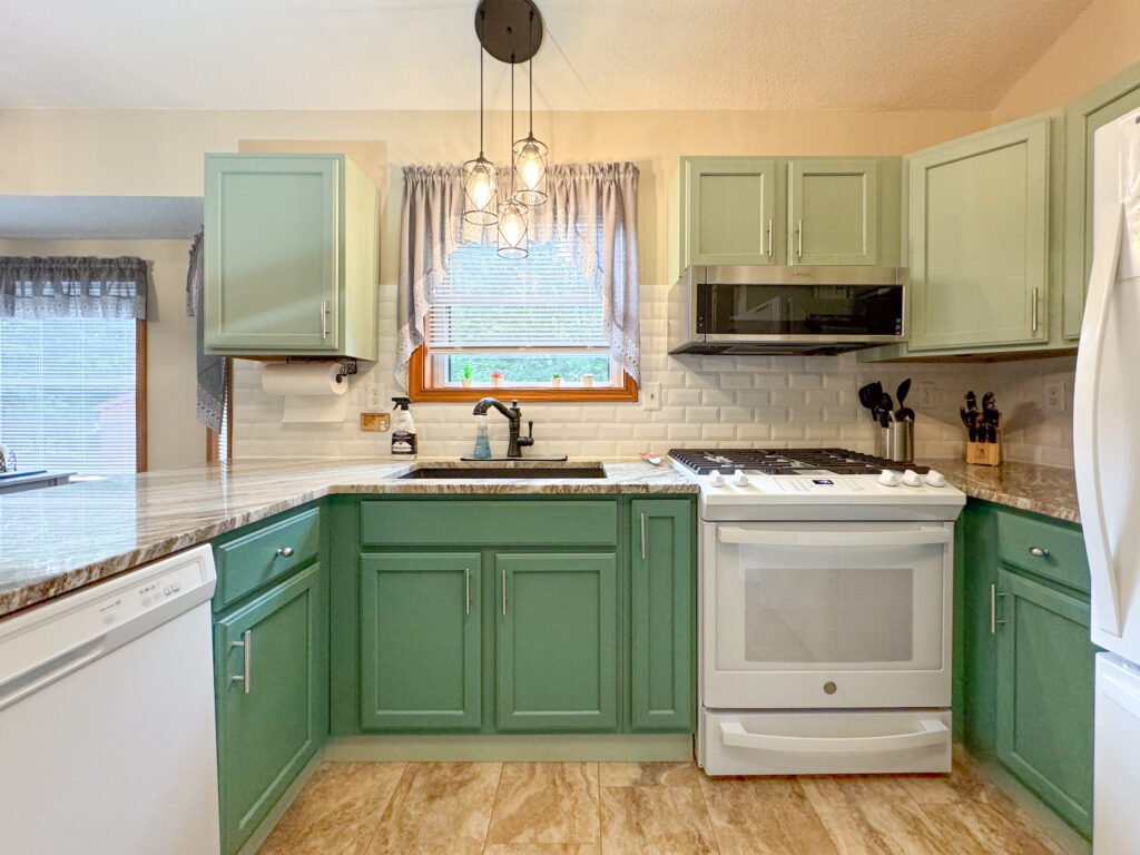 The sunny kitchen with white appliances and aspen green cabinets at the Quiet Pond Lookout vacation rental property.